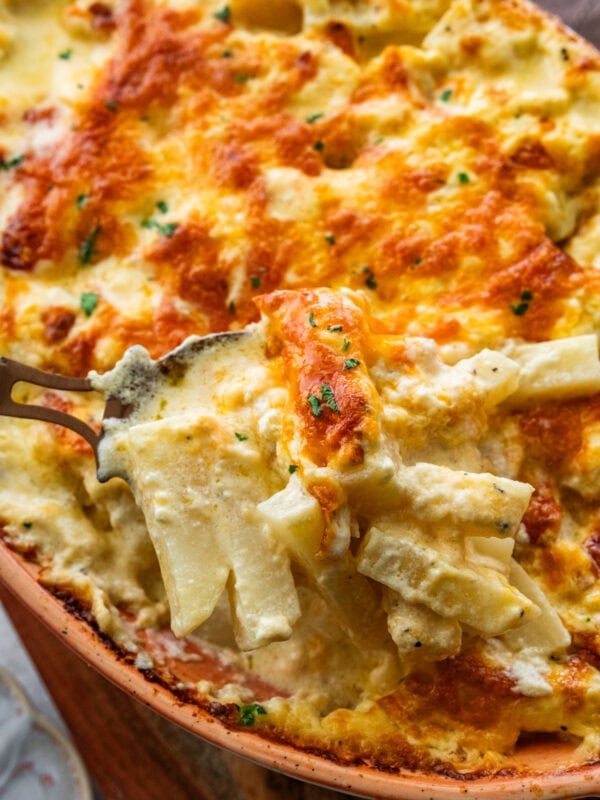 Serving spoon lifting a portion of the cheesy potatoes.