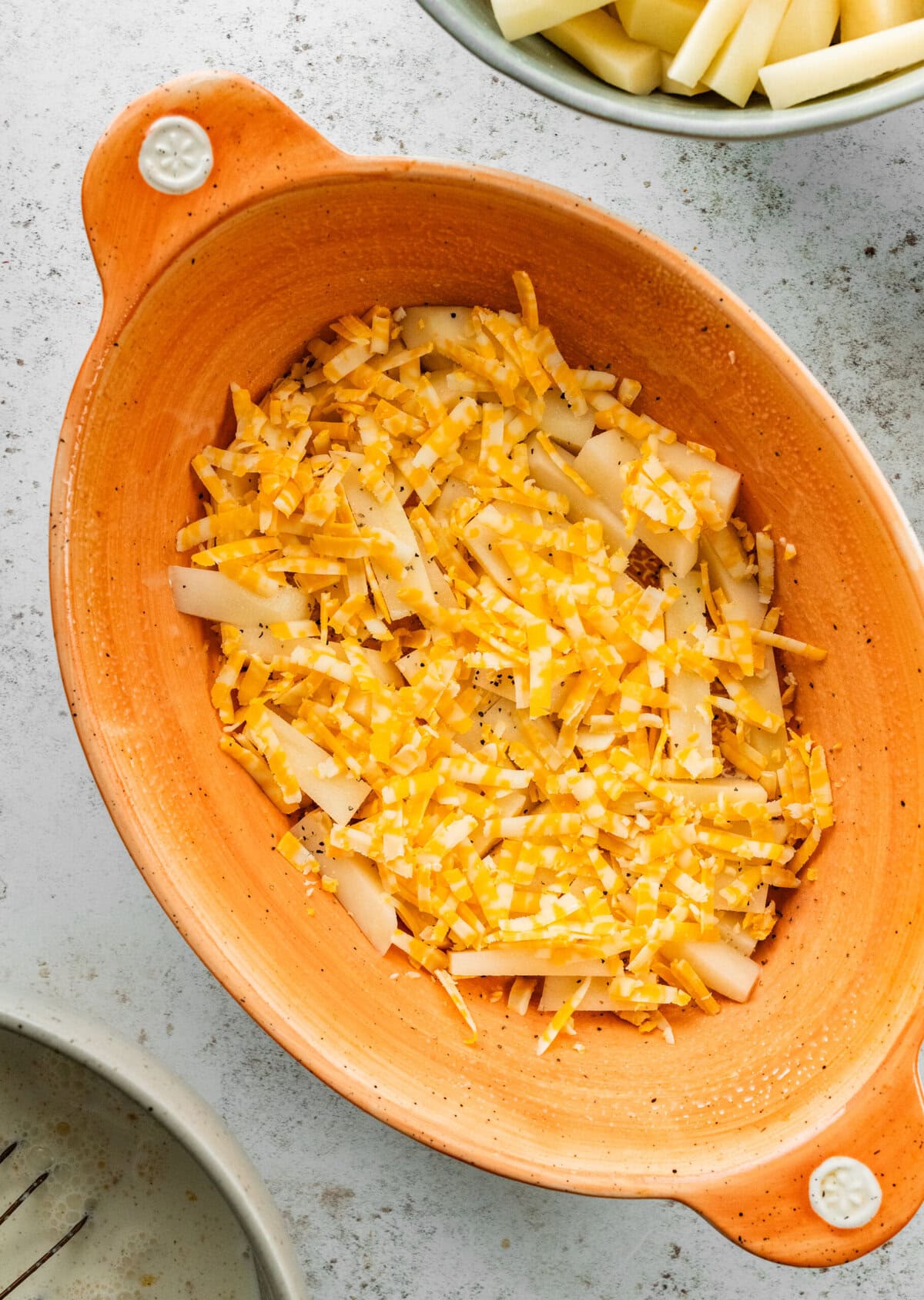 layering the potatoes in the casserole with the cheese.