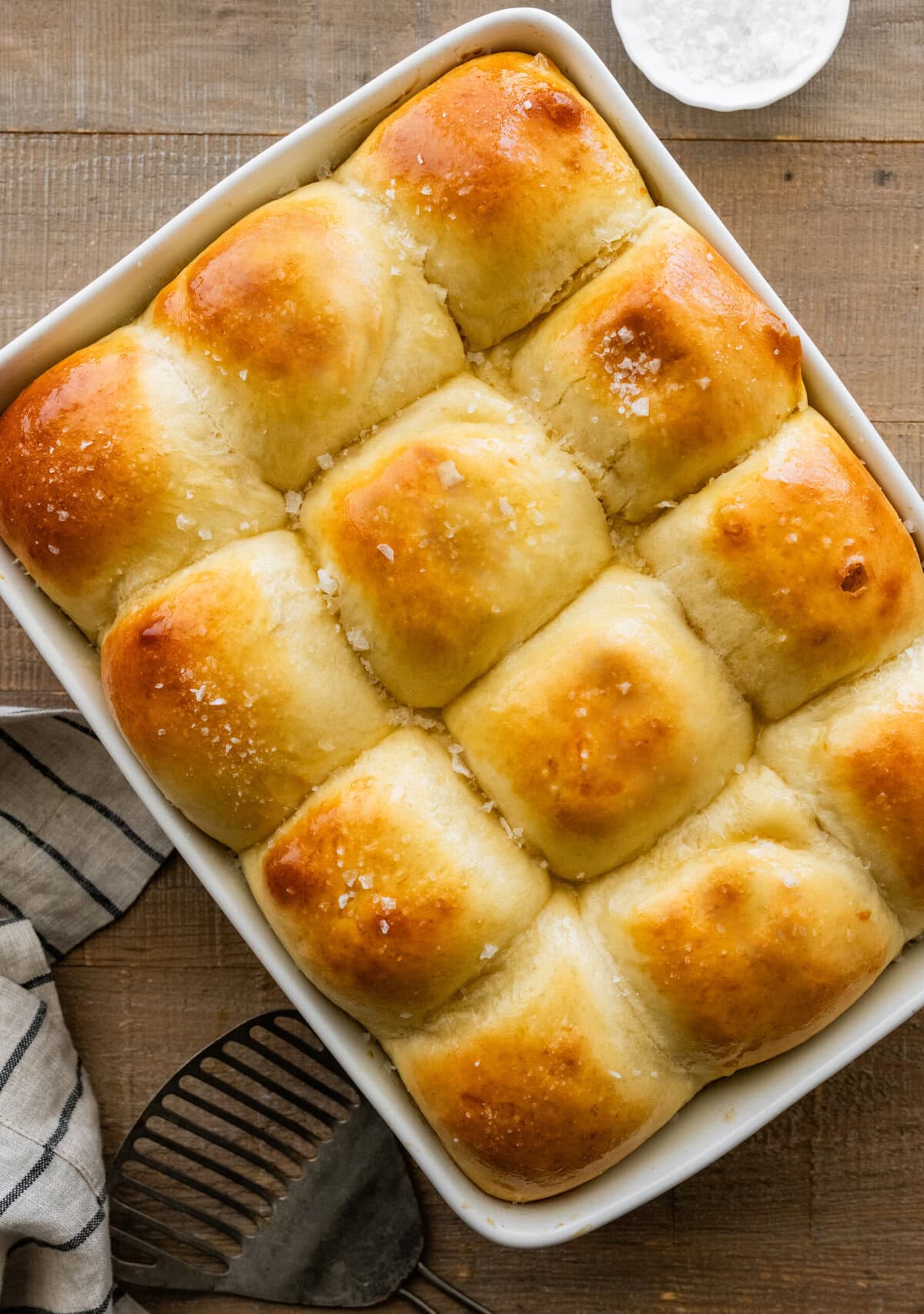 easy dinner rolls in a baking dish with golden brown tops with butter and salt on top.