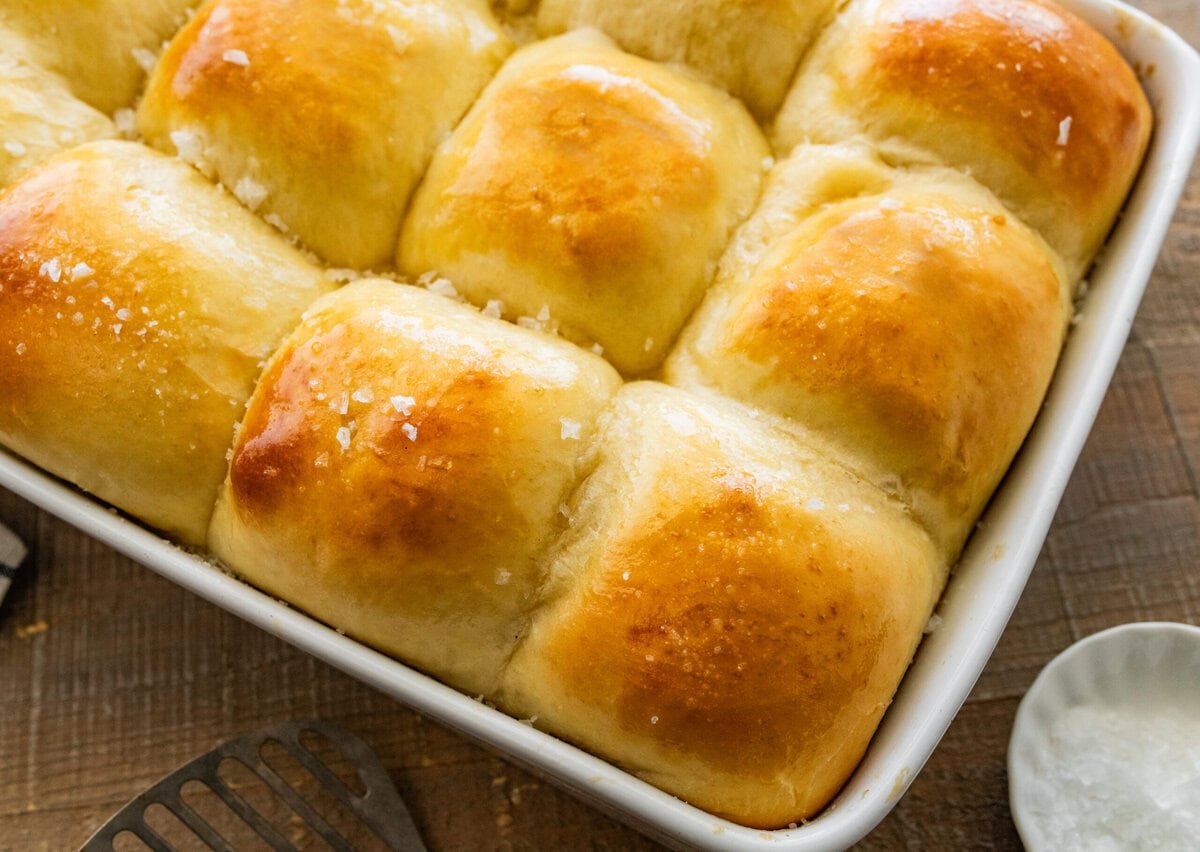 easy dinner rolls in a baking dish with golden brown tops with butter and salt on top.
