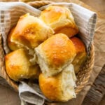 soft and fluffy dinner rolls with golden brown tops in a bread basket.