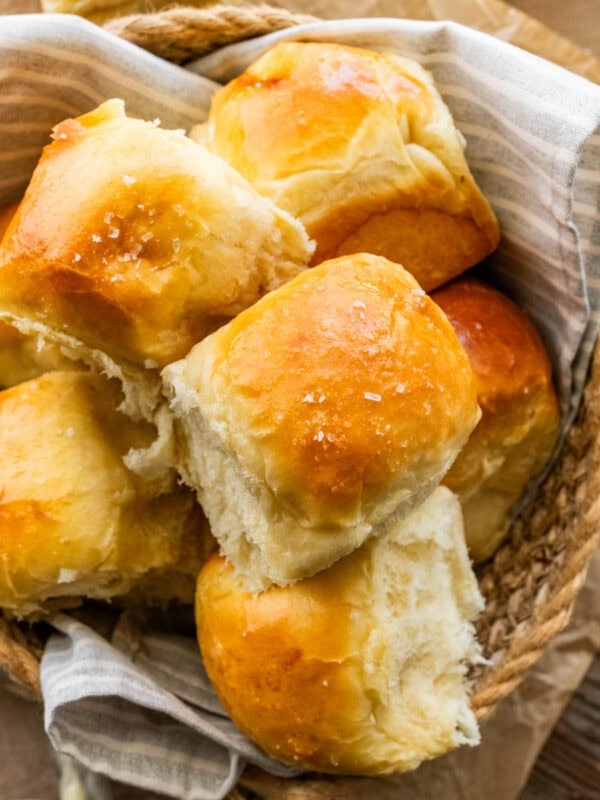 soft and fluffy dinner rolls with golden brown tops in a bread basket.