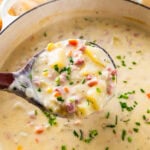 ham and potato soup in a pot with a wooden ladle in it.