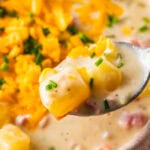 spoon with a bite of the ham and potato soup on it.