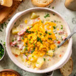 ham and potato soup in a soup bowl with cheese and chives on top. Spoon in bowl.