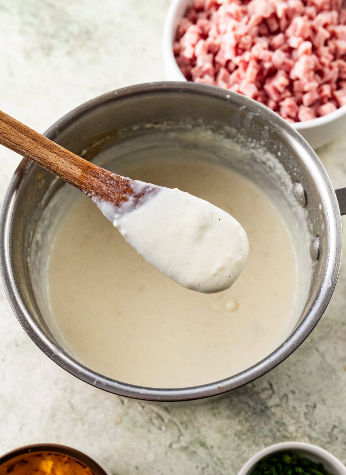 thickened roux in a pot with a wooden spoon showing thickness.