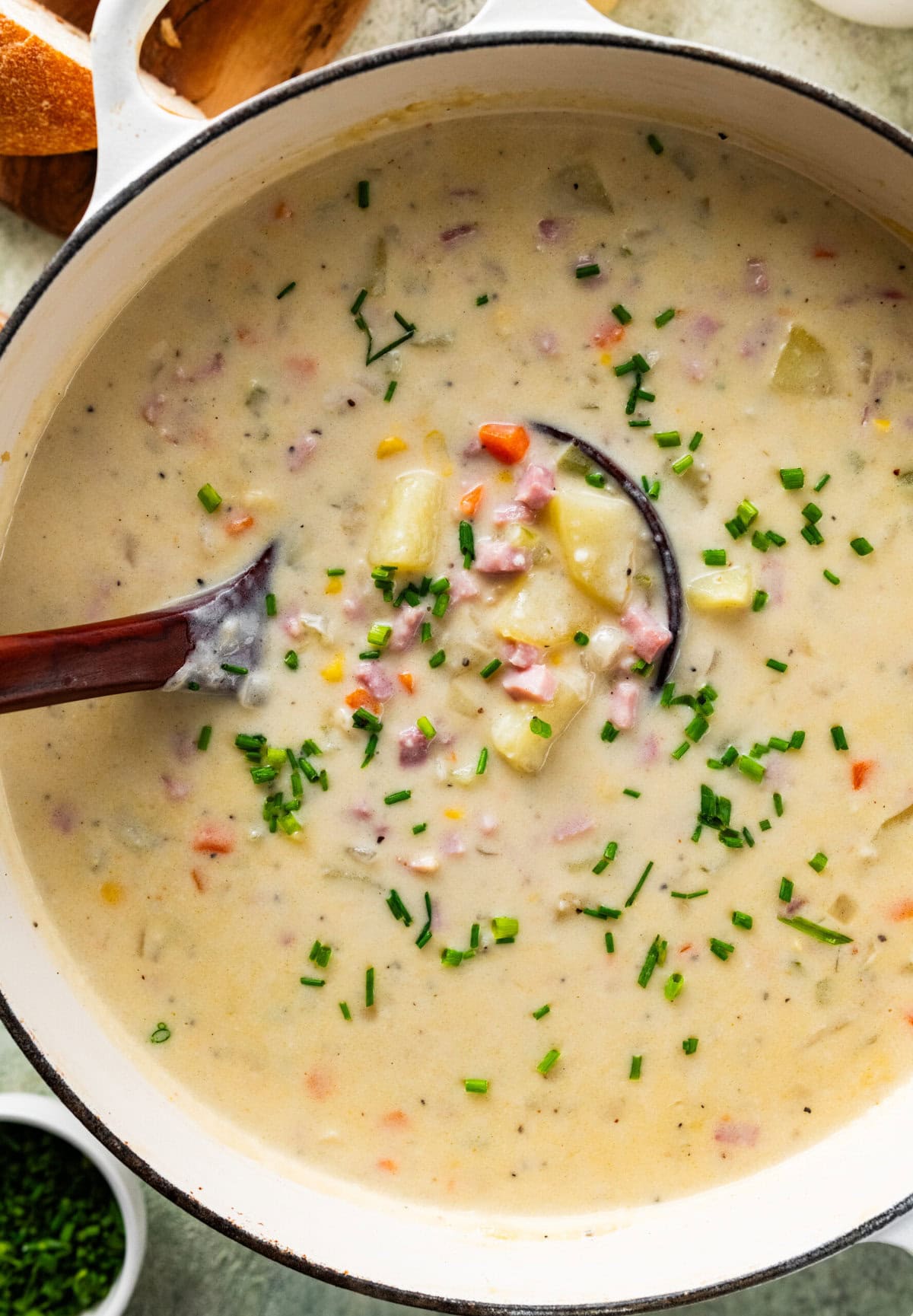 ham and potato soup in a pot with a wooden ladle in it.