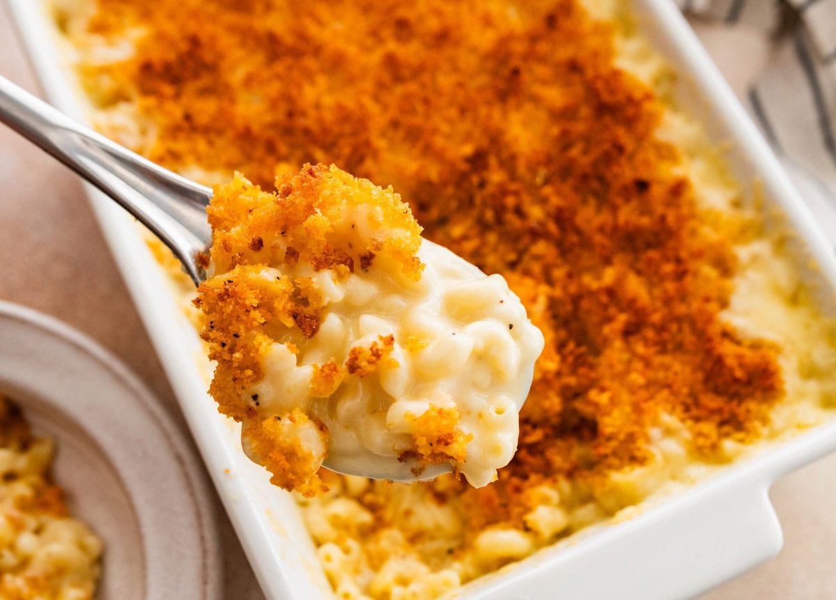 creamy baked mac and cheese in a pan with a serving spoon. 