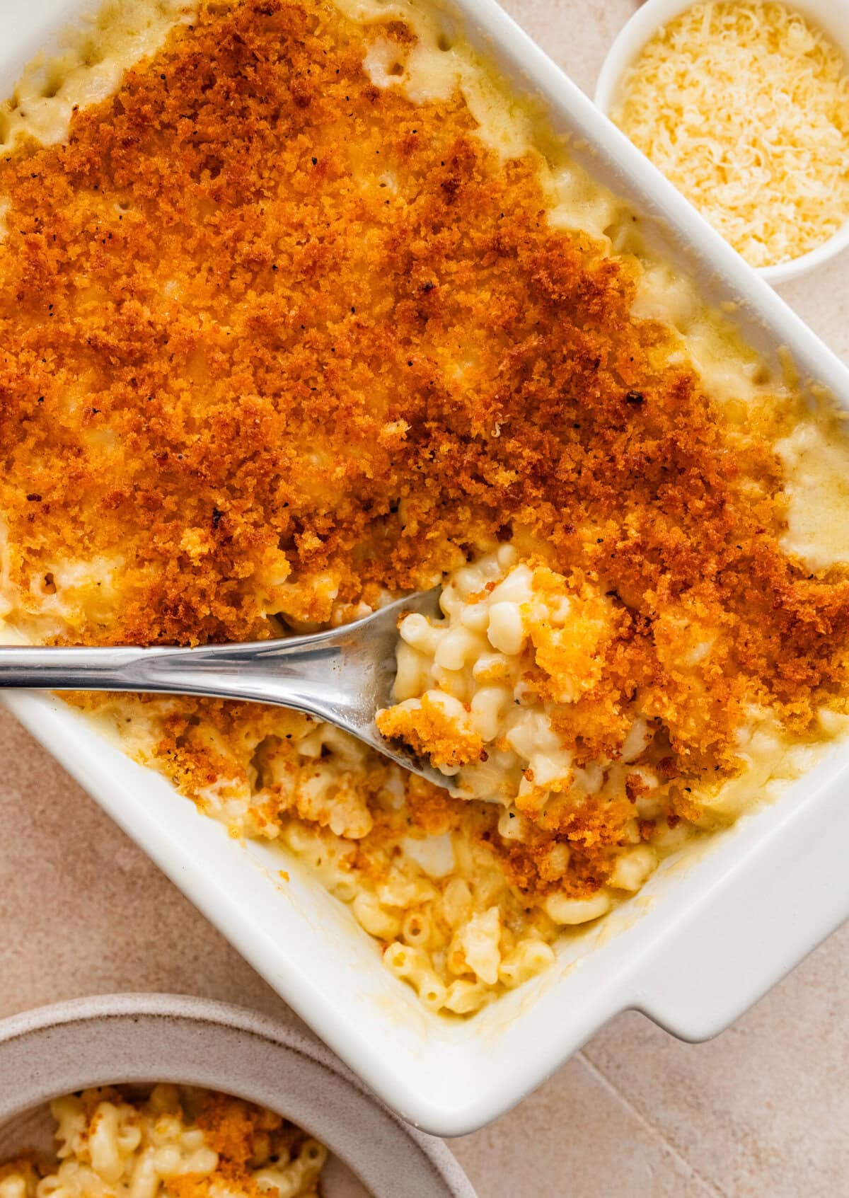 creamy baked mac and cheese in a pan with a serving spoon.