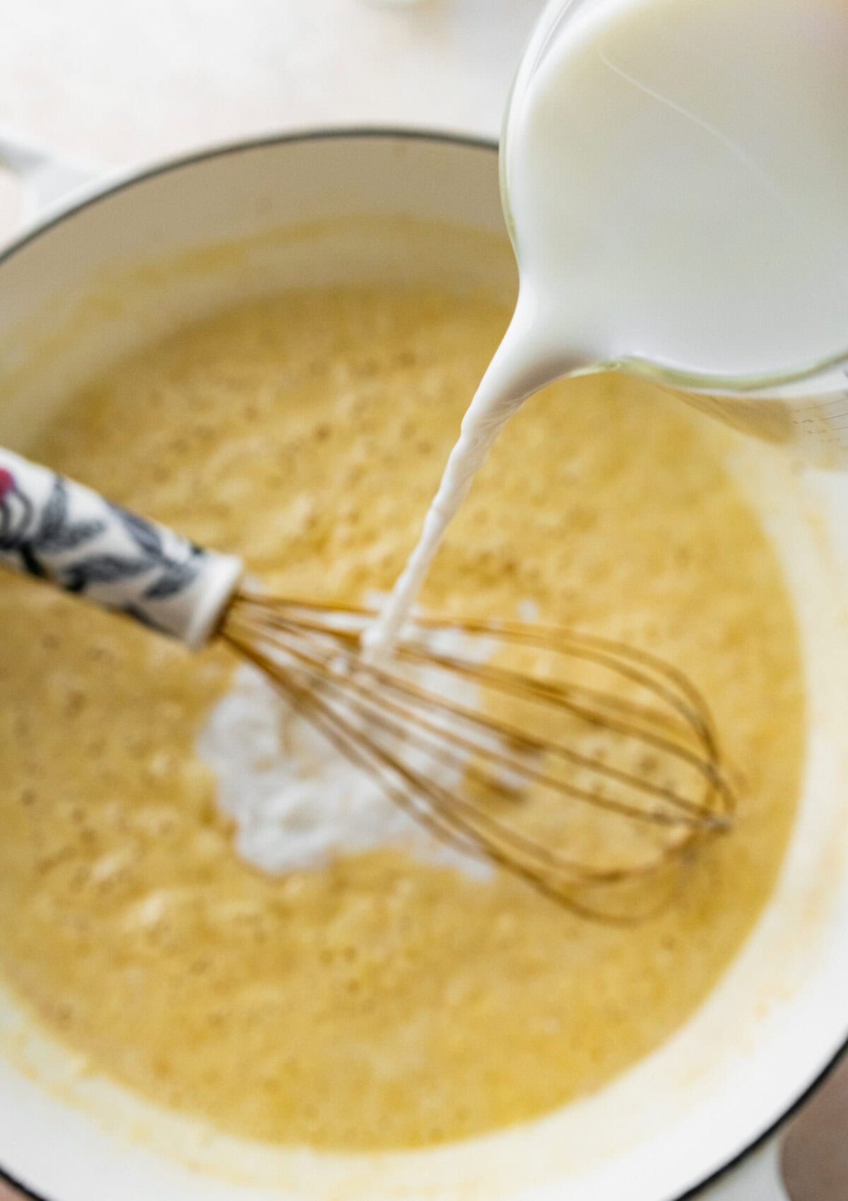pouring milk in the pan with roux for the homemade mac and cheese