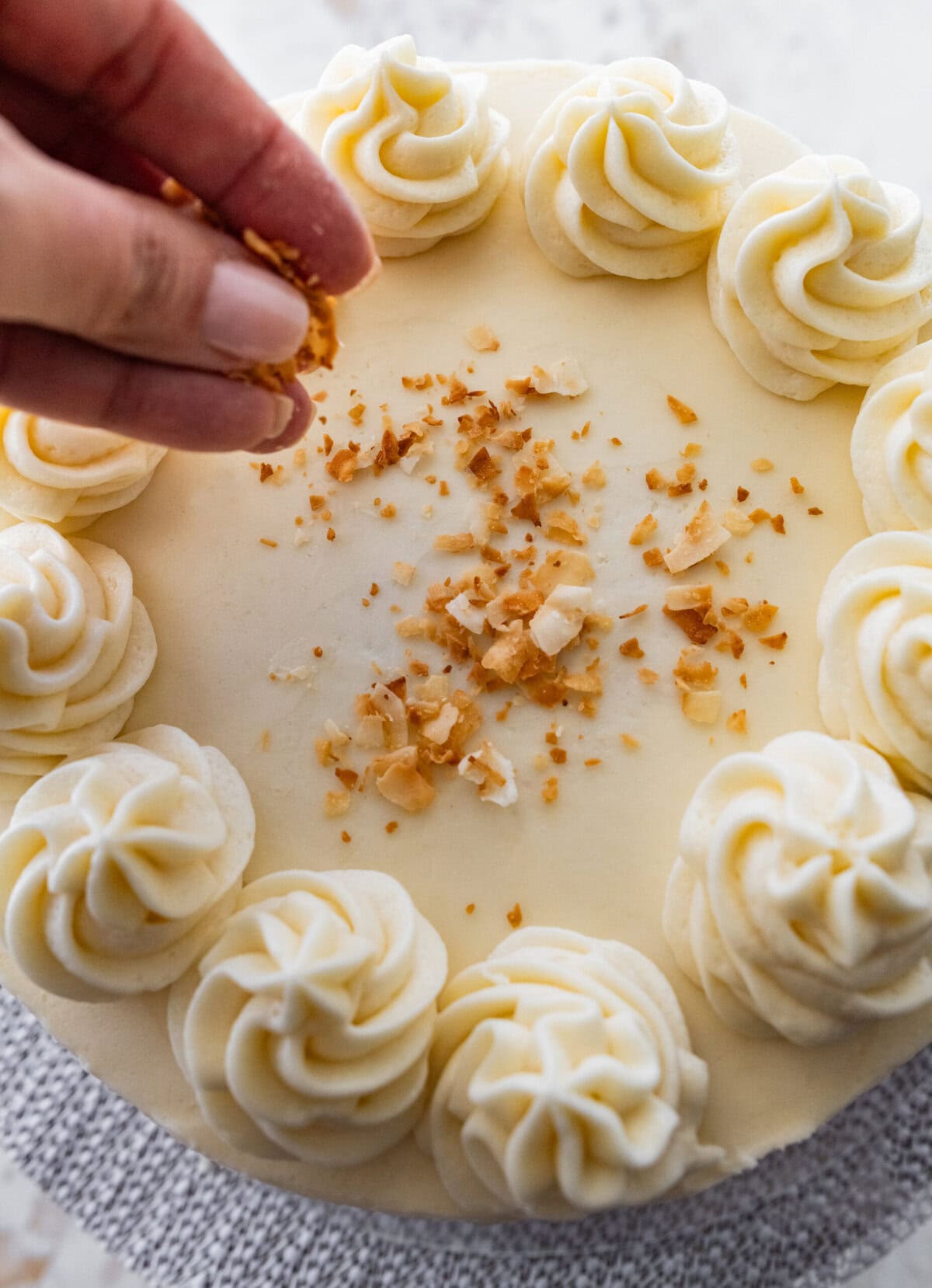 hand sprinkling chopped nuts in the middle of the finished cake.