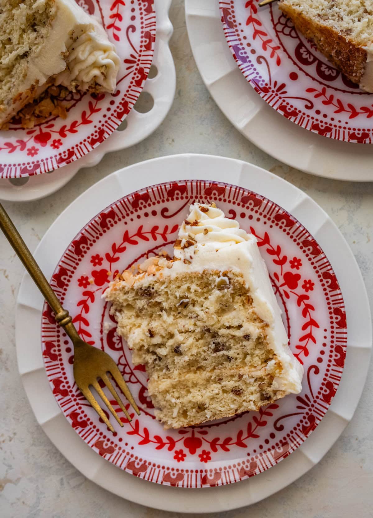 Slice of Italian cream cake on an red and white antique dessert plate.