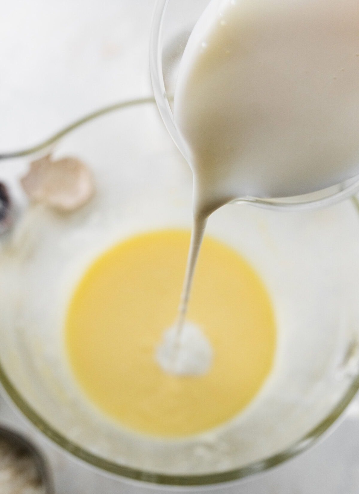 pouring milk into bowl with beaten eggs and sugar.