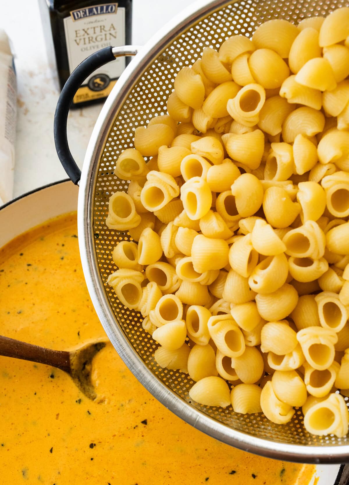 pouring the pasta into the pan with the sauce.