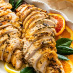 roast turkey breast sliced on a platter with oranges and lemons around it.