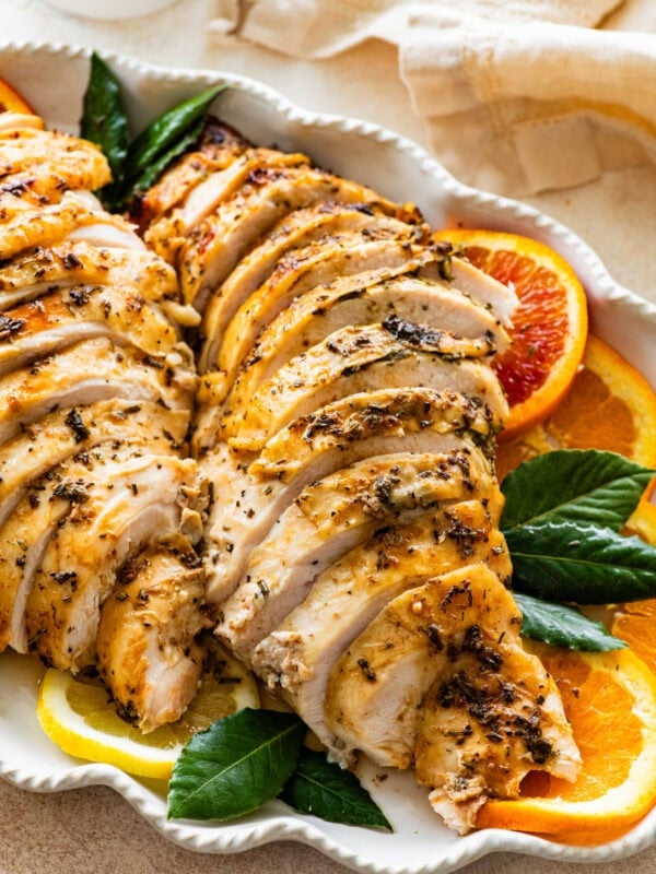 roast turkey breast sliced on a platter with oranges and lemons around it.