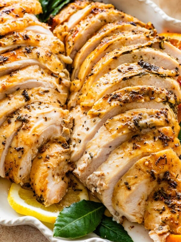 roast turkey breast sliced on a platter with oranges and lemons around it.