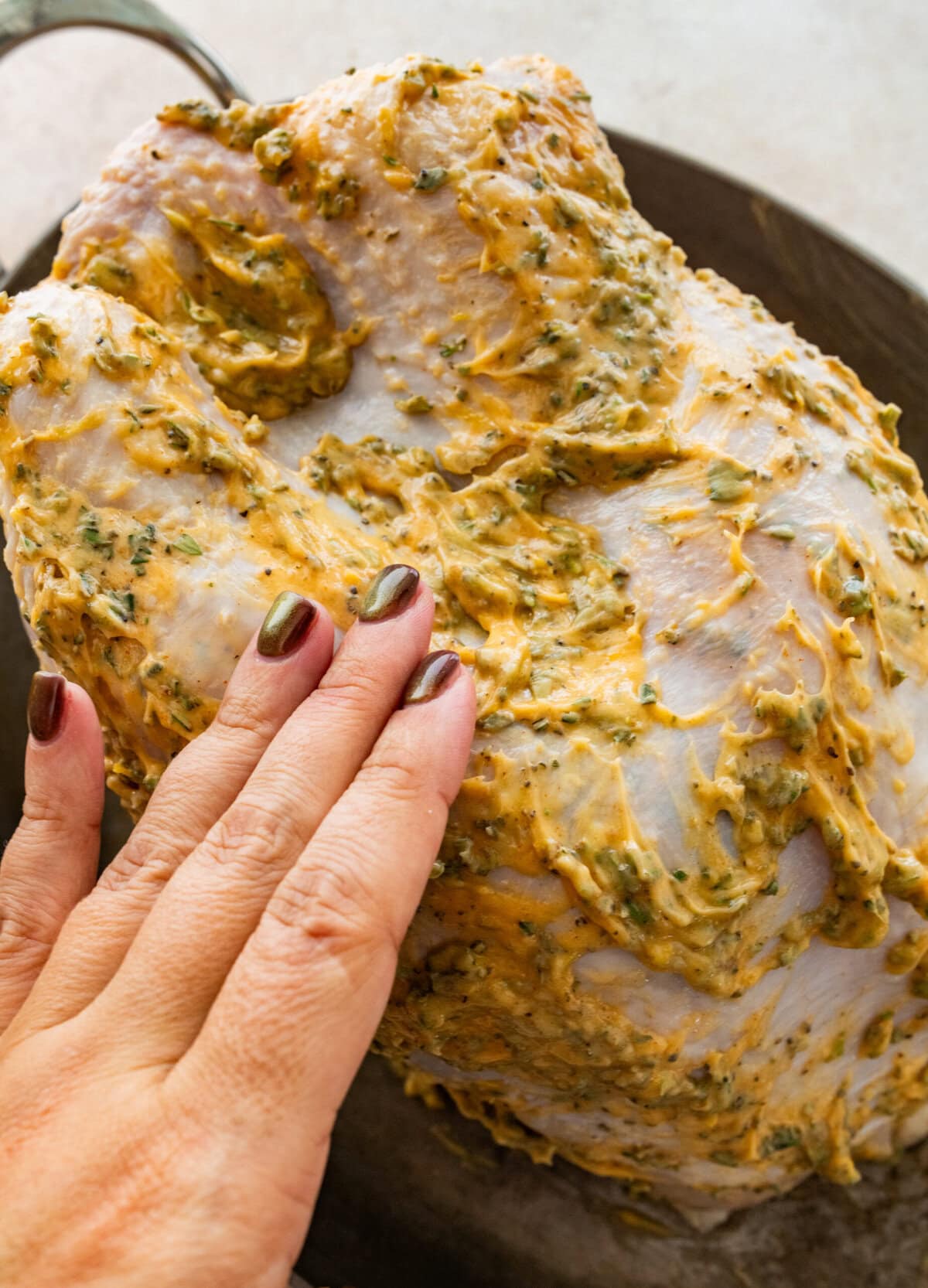 A person rubbing turkey herb butter on the turkey breast.