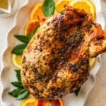 roast turkey breast on a platter with lemon and orange slices around it.