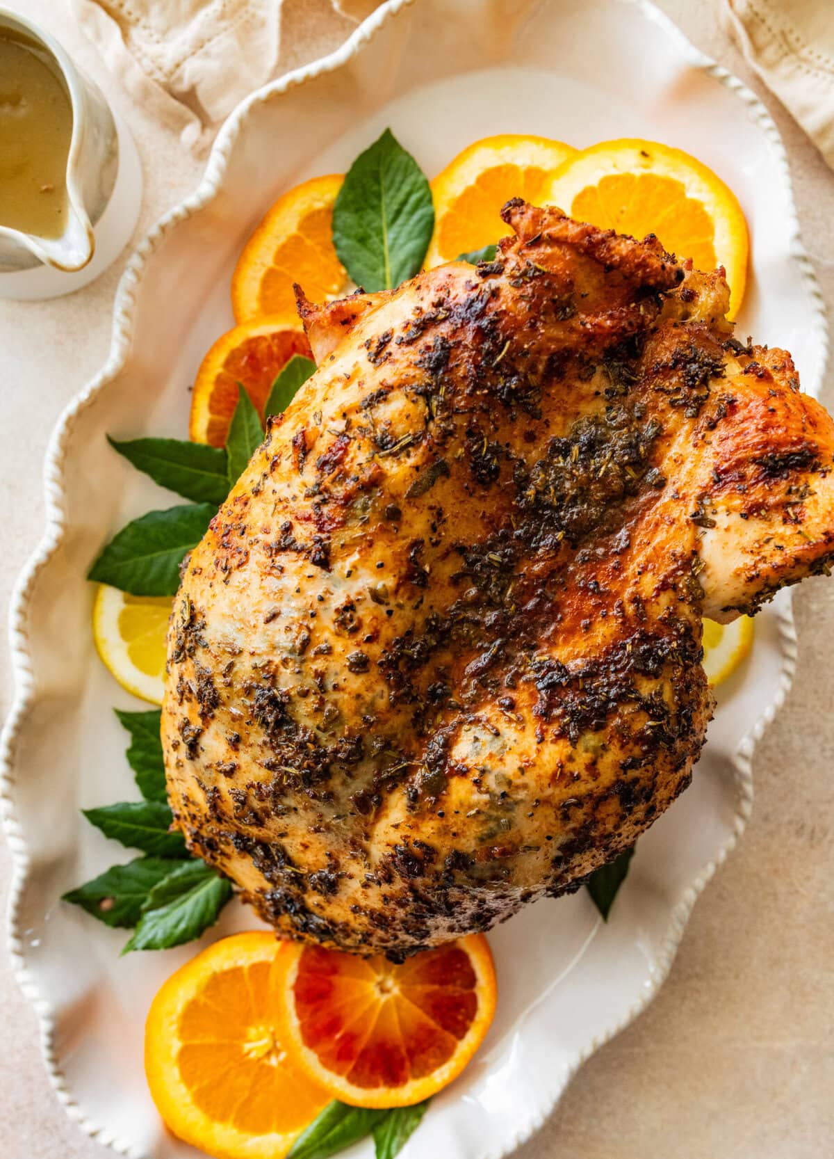 roast turkey breast on a platter with lemon and orange slices around it.