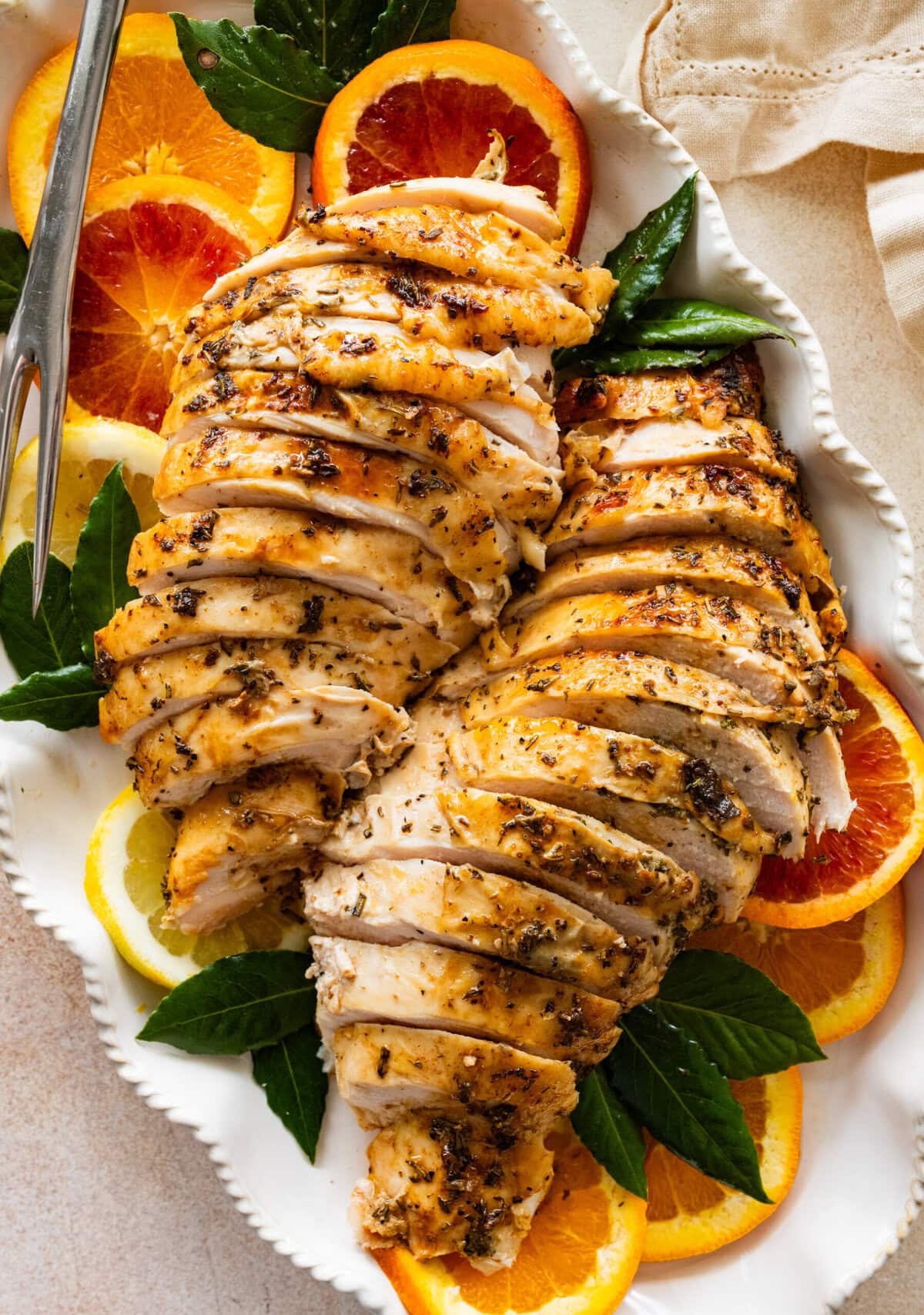 roast turkey breast sliced on a platter with oranges and lemons around it.
