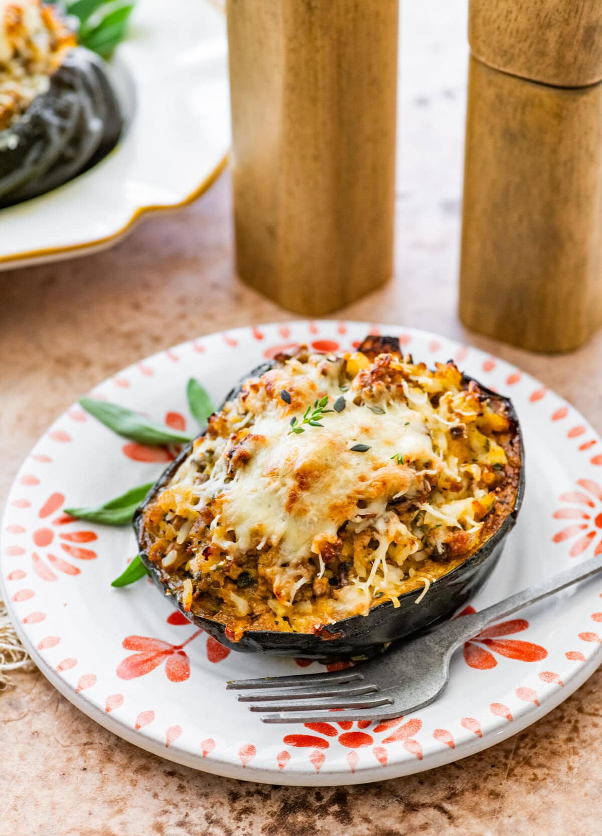 one baked acorn squash with cheesy topping on a plate with a fork.