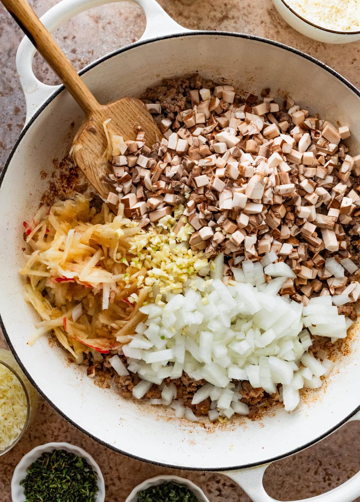 onions and spices added to ground sausage in pan.