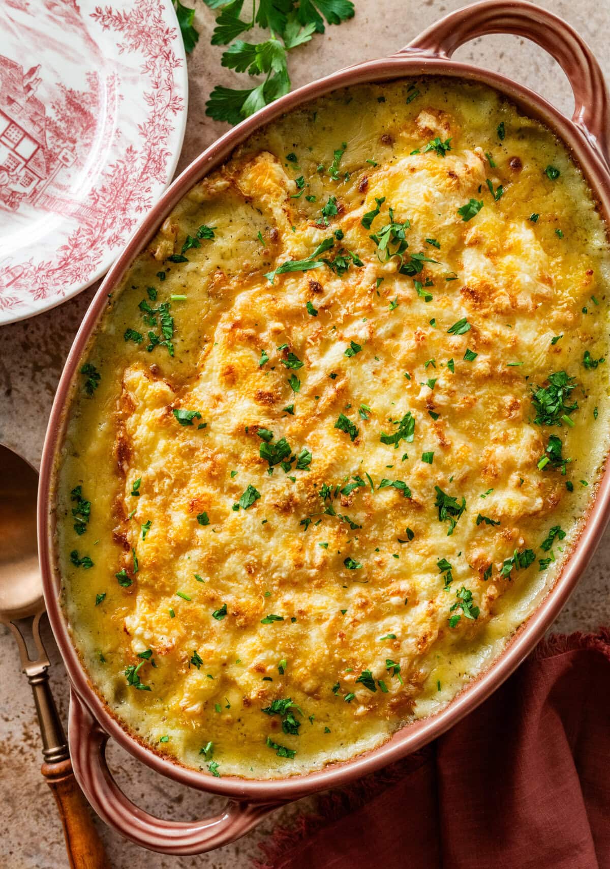 golden and bubble turkey shepards pie in a casserole dish with garnish of parsley on top.