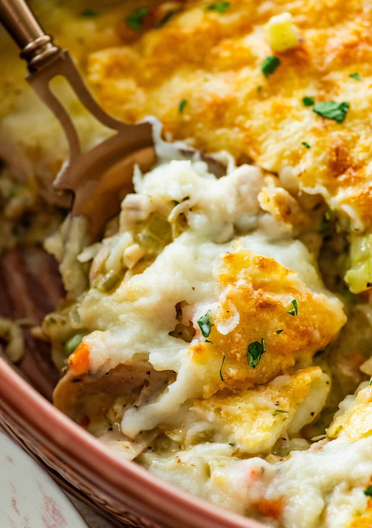 serving spoon dishing out a spoonful of turkey shepards pie from casserole dish.