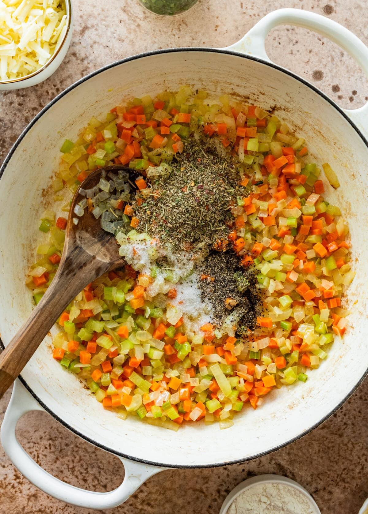 diced carrots, onions, and celery with spices in a pot.