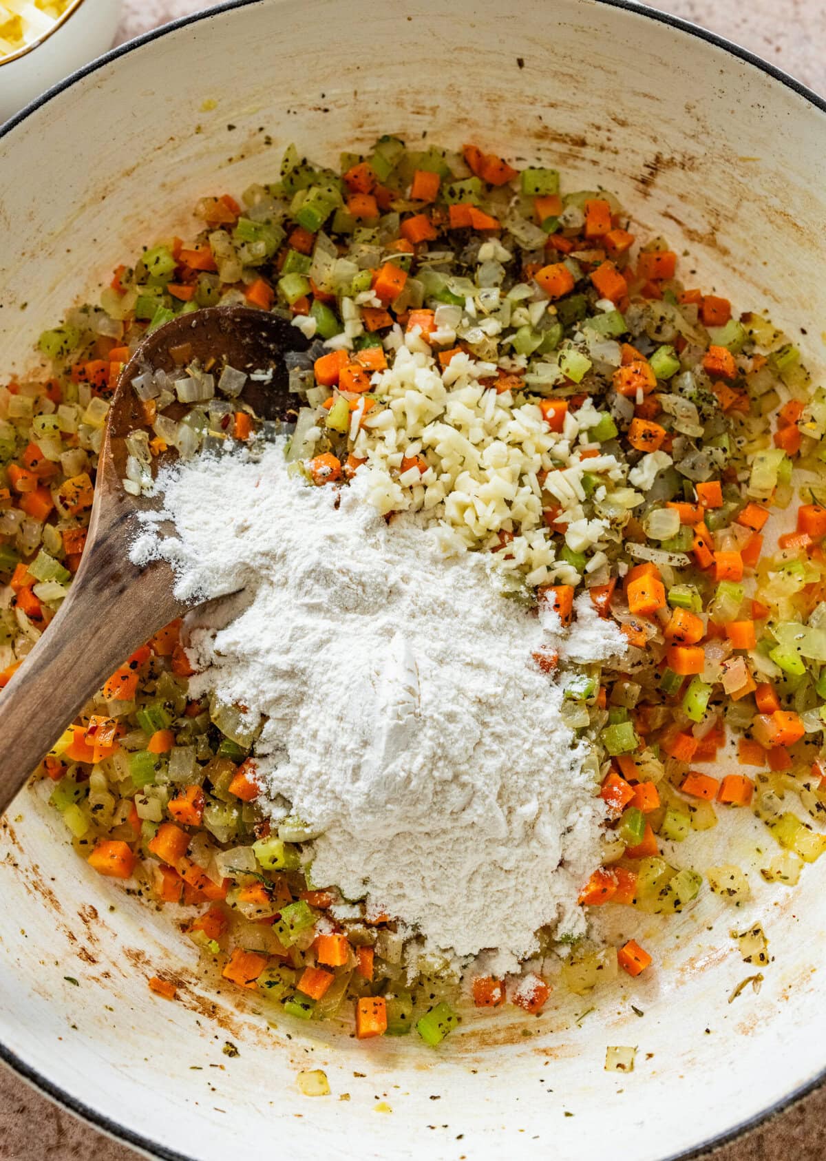 diced carrots, onions, celery, and flour with spices in a pot.
