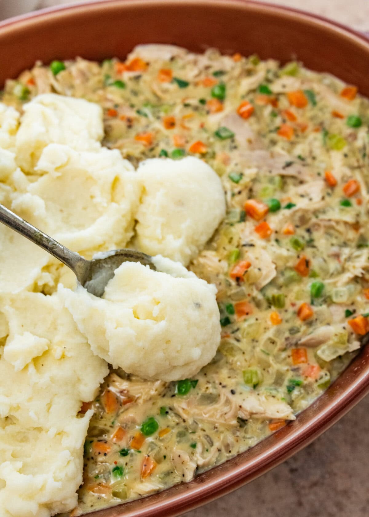 add mashed potatoes to the top of the casserole with turkey filling.