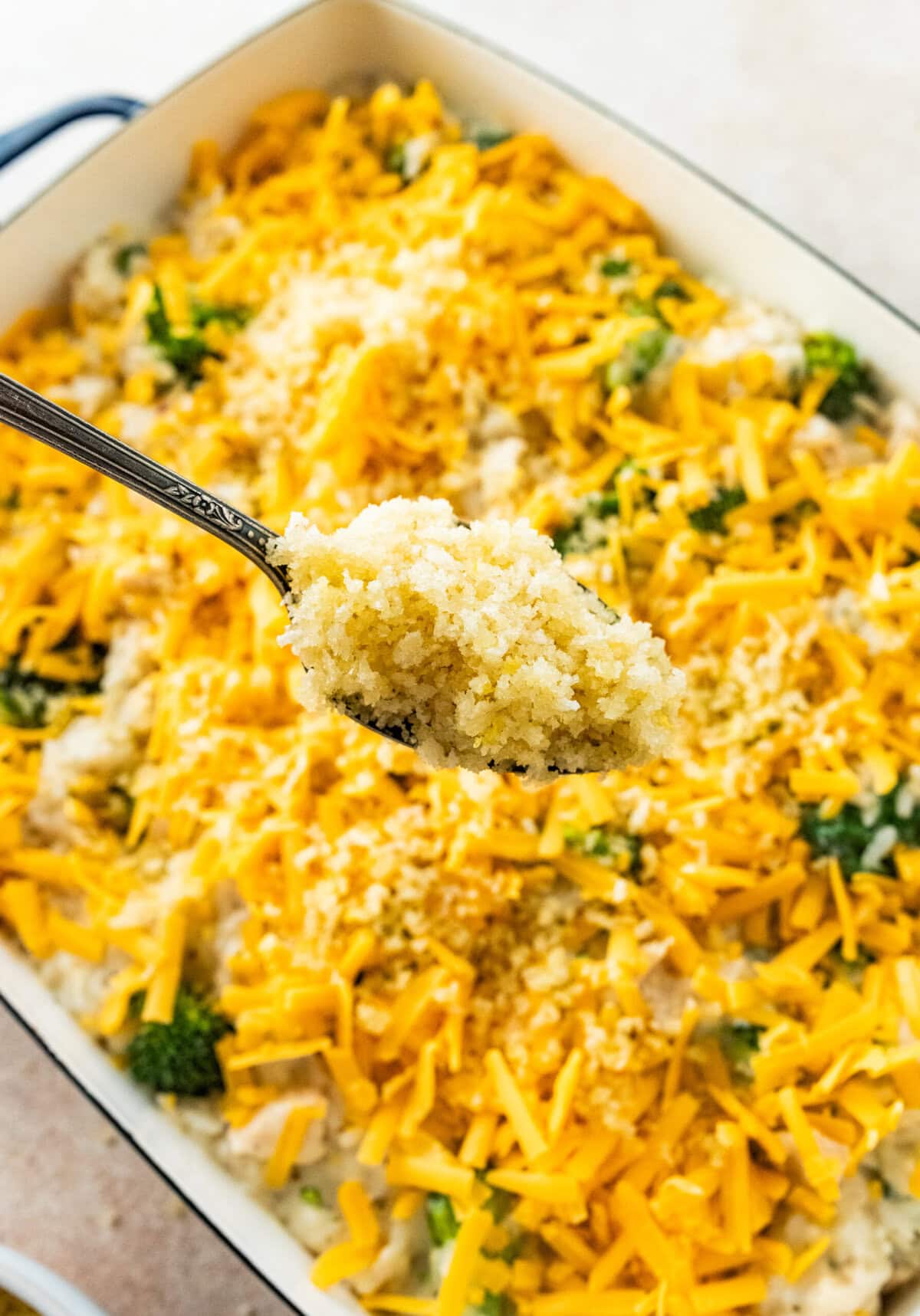 baked chicken, broccoli, and rice in a casserole dish ready to bake. Spoon sprinkling crunchy topping on the top.