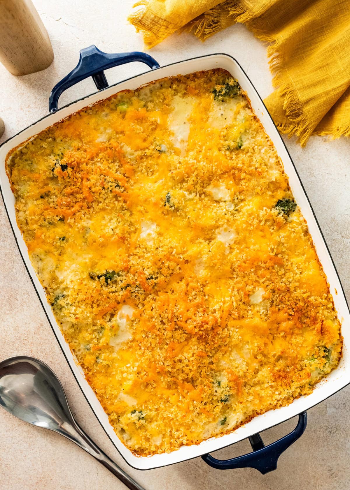 baked chicken and broccoli casserole in a white baking cheese with melty cheese on the top.