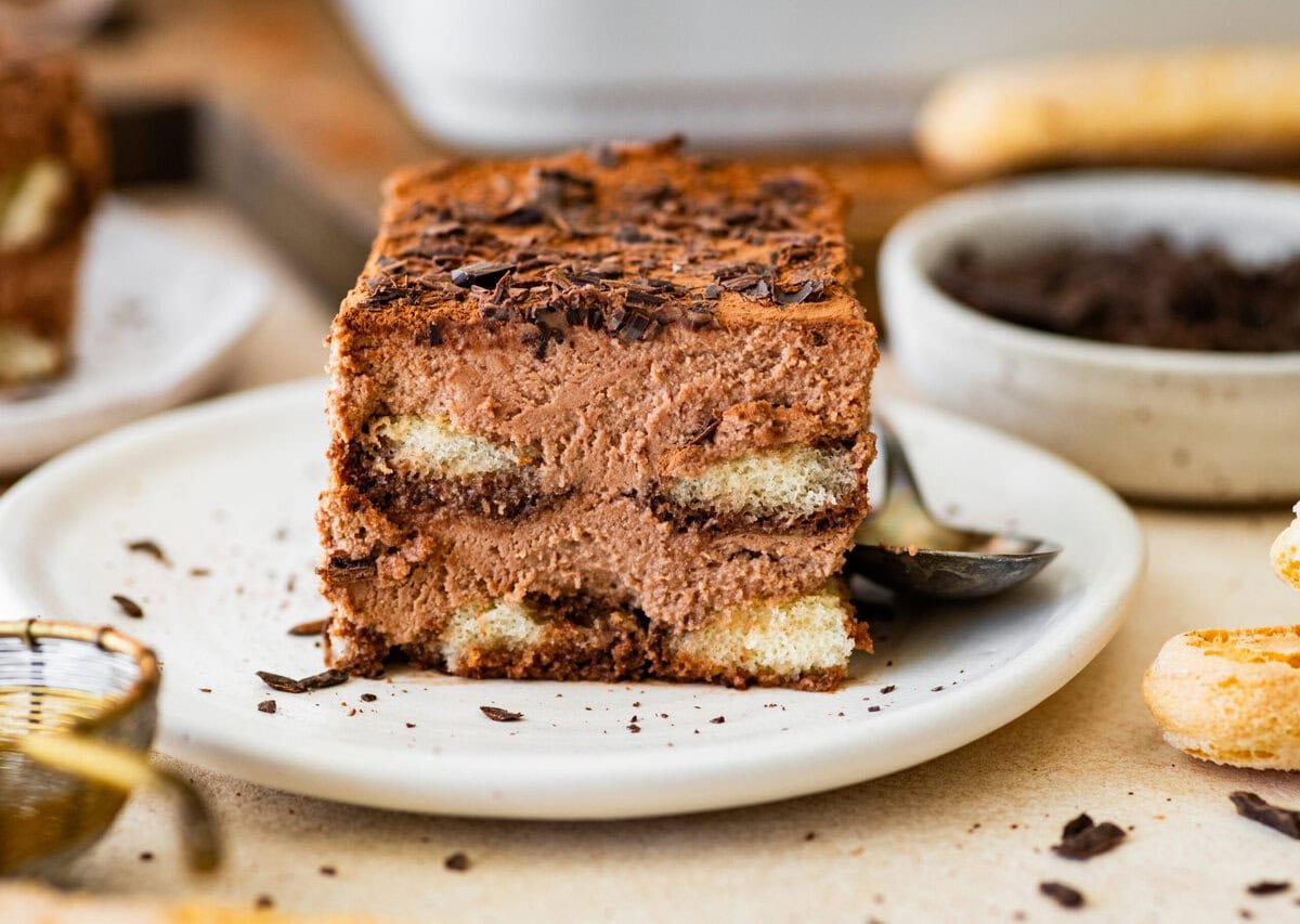 a slice of chocolate tiramisu on a white serving plate ready to eat. 