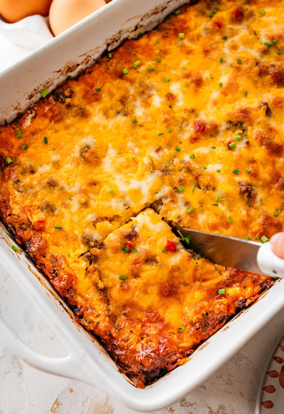 knife cutting a square of the breakfast casserole.
