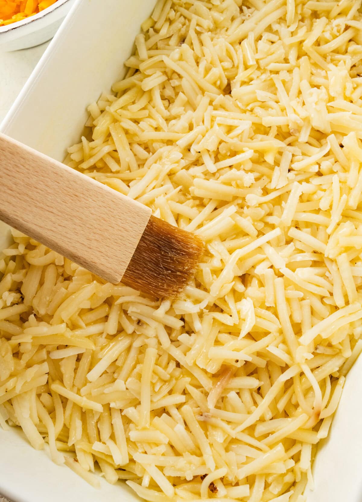 add hashbrowns to the bottom of the pan and brush with butter.