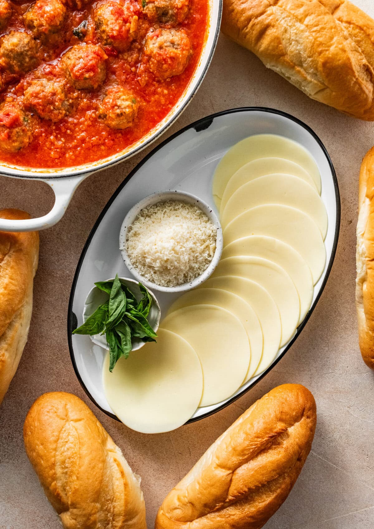 topping ingredients for Italian meatball subs including bread rolls and cheese.