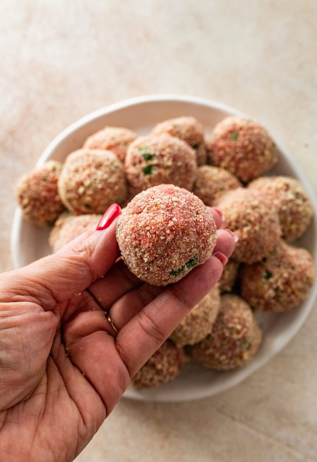 hand holding rolled Italian meatballs.