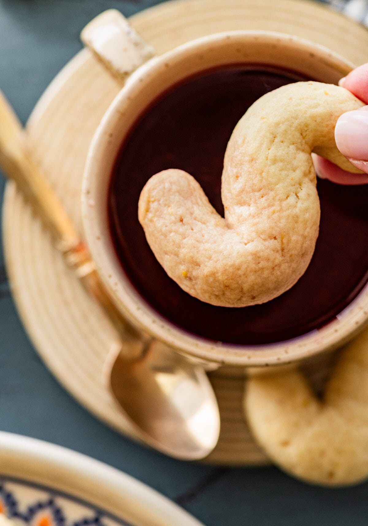hand dipping an Italian S cookie in a warm cup of tea.