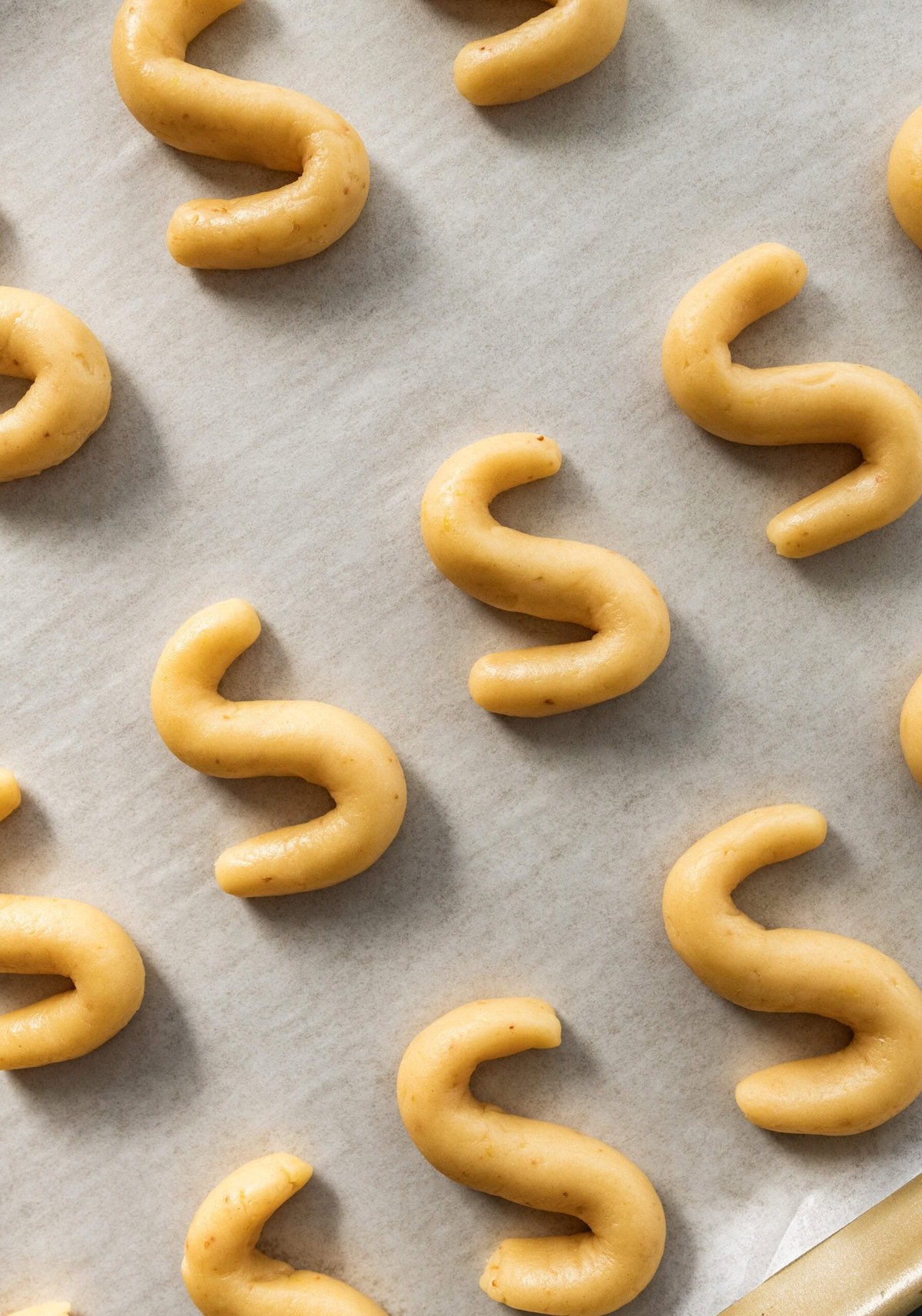 cookie sheet lined with parchment with "s" cookies lined in a row.