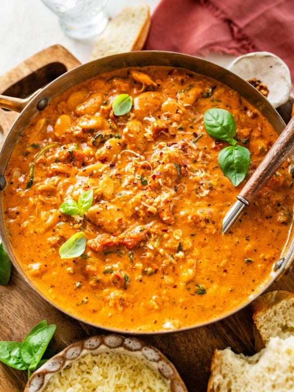 serving dish with creamy marry me butter beans with a serving spoon holding some to serve.