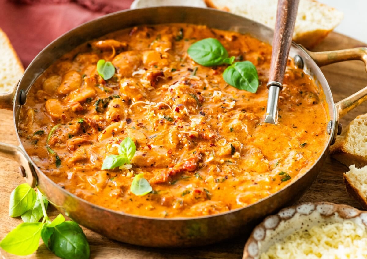 serving dish with creamy marry me butter beans with a serving spoon holding some to serve.