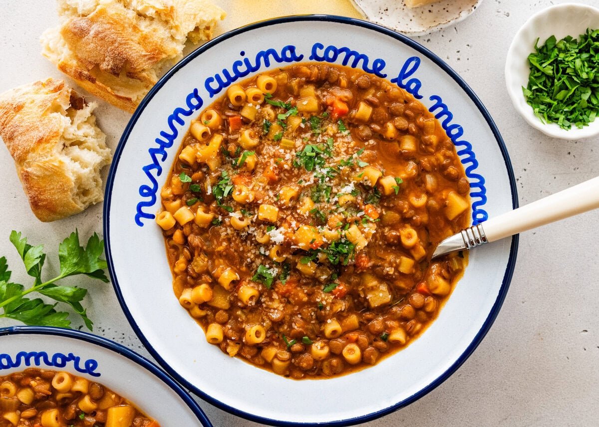 Italian bowl with cooked lentils and pasta in it with a spoon.