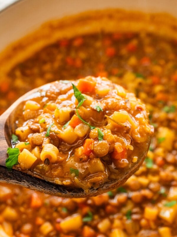 cooked lentils and pasta in pot with wooden ladle.