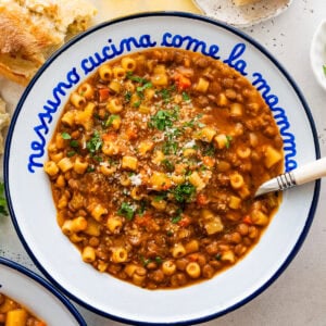 Italian bowl with cooked lentils and pasta in it with a spoon. Crusty bread on the side.