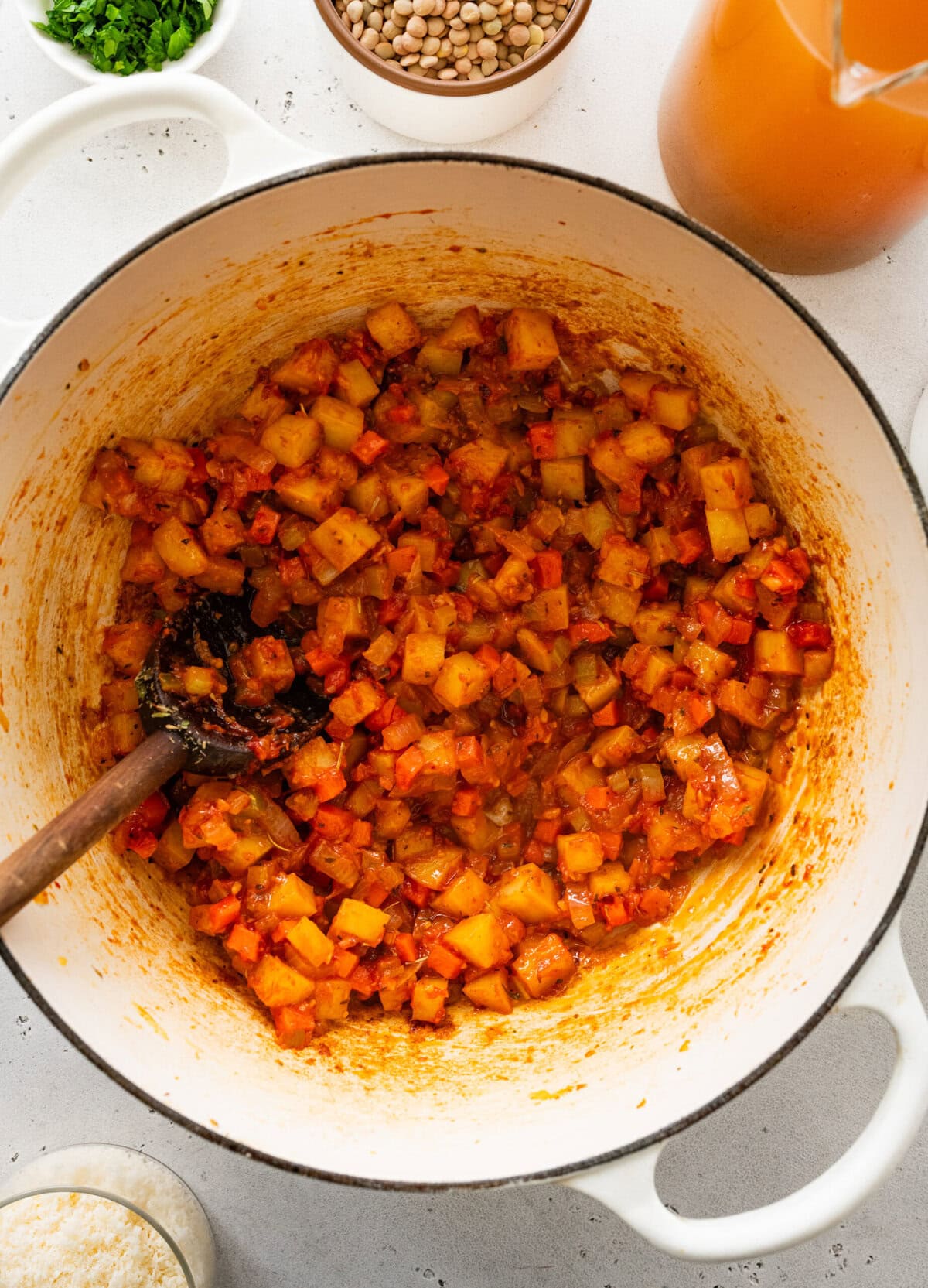 cooked potatoes, carrots, and onions celery in pot with tomato paste.