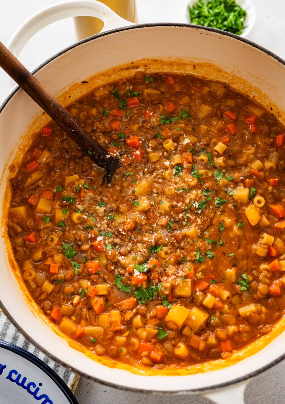 cooked lentils and pasta in pot with wooden ladle.