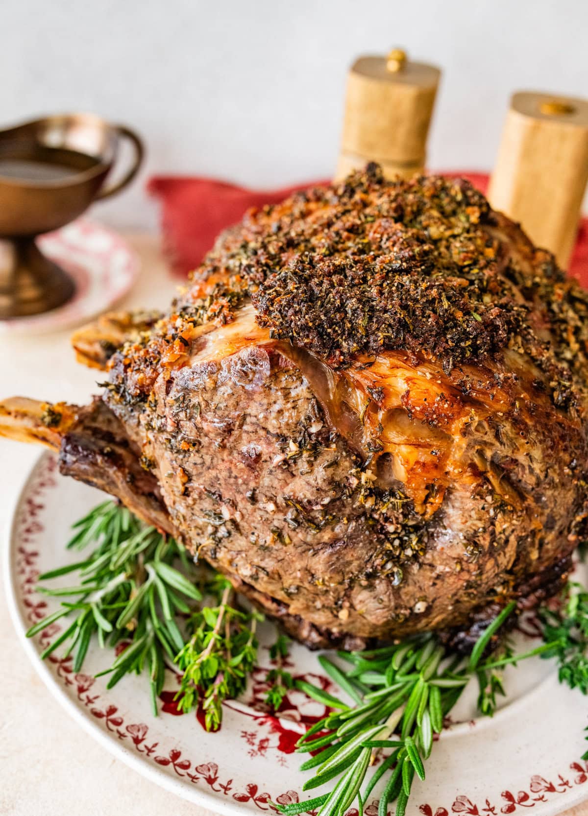 standing prime rib roast recipe on a platter with herbs around it.