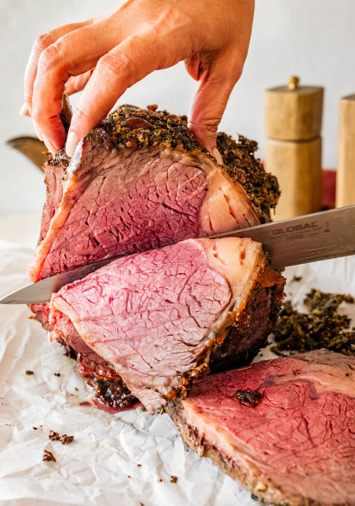 knife cutting the standing prime rib roast so you can see perfectly cooked inside of the meat.
